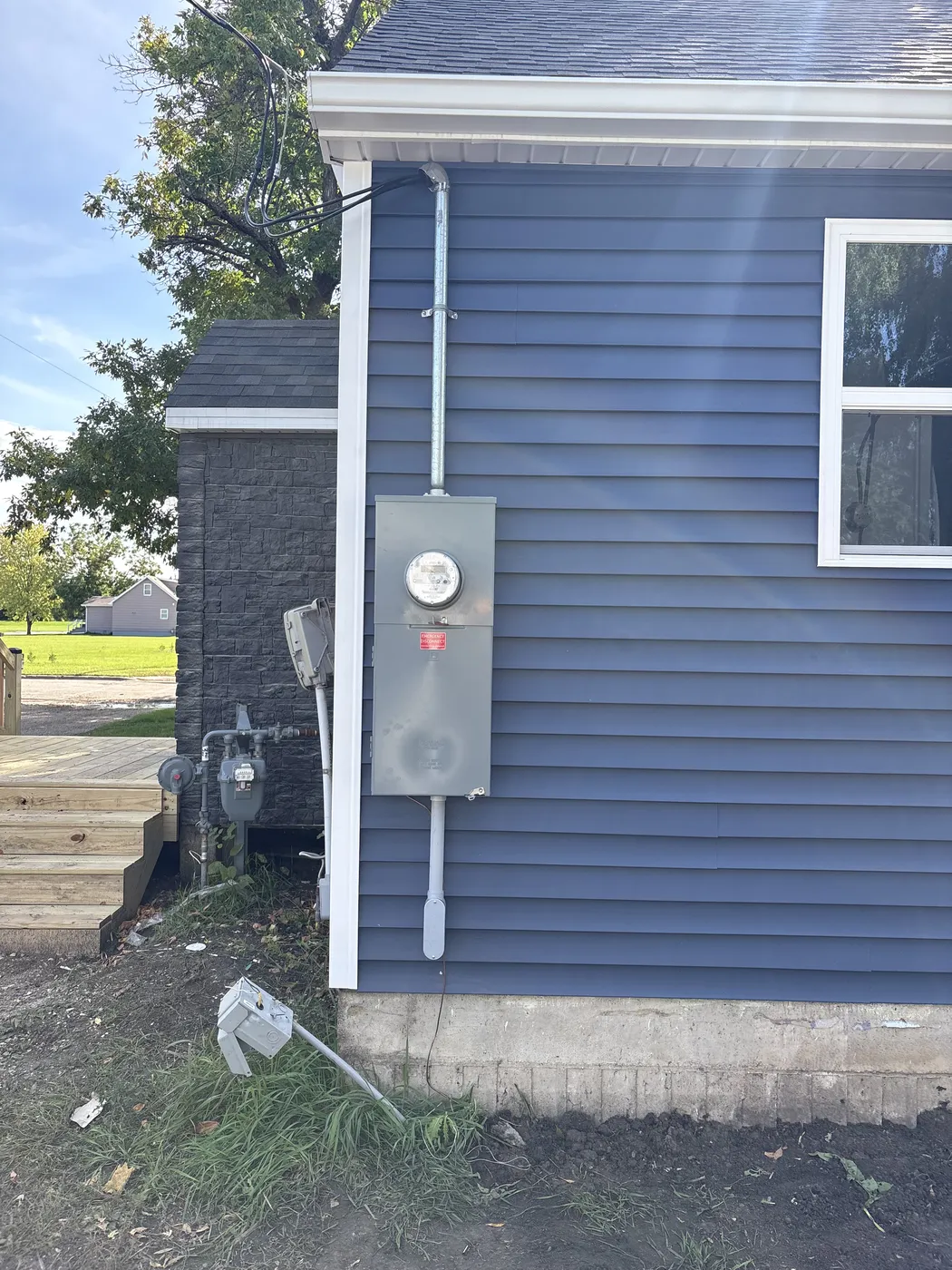 New outdoor meter-main combination panel and service mast mounted on new blue siding at a renovated home in Grygla, Minnesota